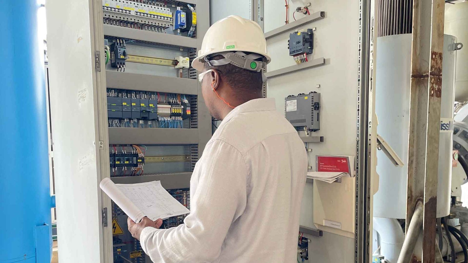 Equipe técnica realizando manutenção industrial em painel elétrico